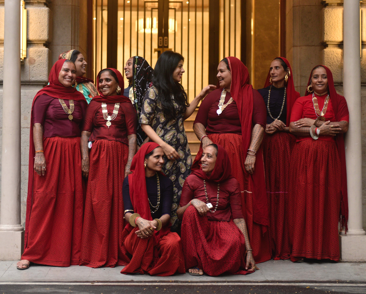 Group of women in traditional red attire with gold jewelry celebrating cultural heritage